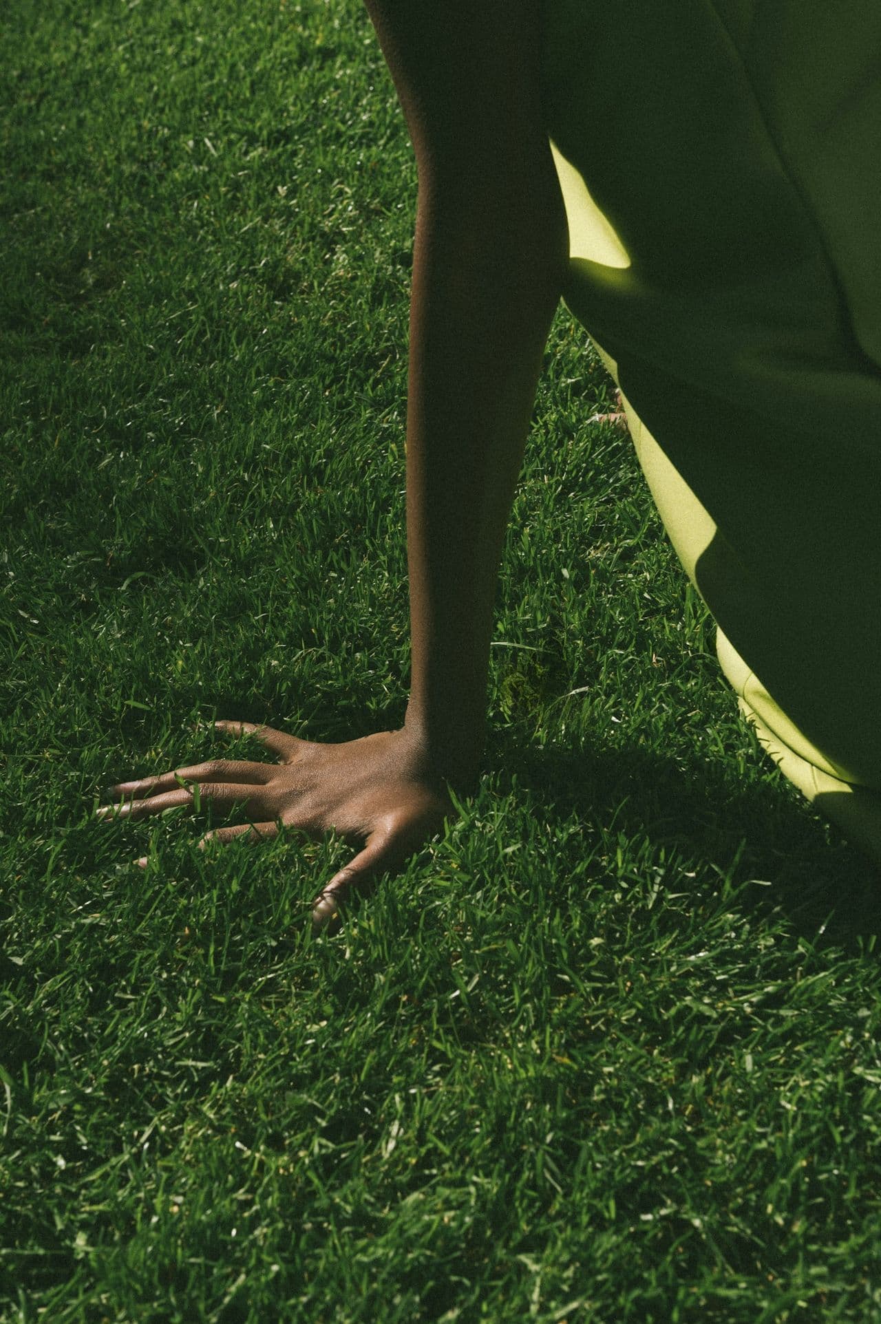 Close-up of a person’s hand touching grass in sunlight — a calm, grounding visual symbolizing connection between the body and nature, used in Samphire Neuroscience content on menstrual well-being and brain-body balance.